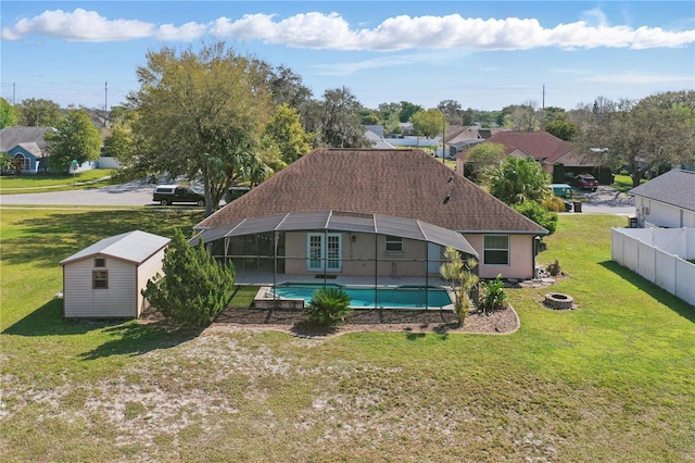 rear view of property with a shed, an outdoor structure, a shingled roof, an outdoor pool, and a lanai