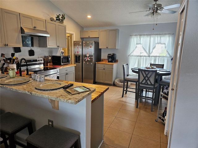 633 Kangaroo Dr, Kissimmee, FL 34759 - kitchen with light tile patterned flooring, ceiling fan, stainless steel appliances, under cabinet range hood, and lofted ceiling