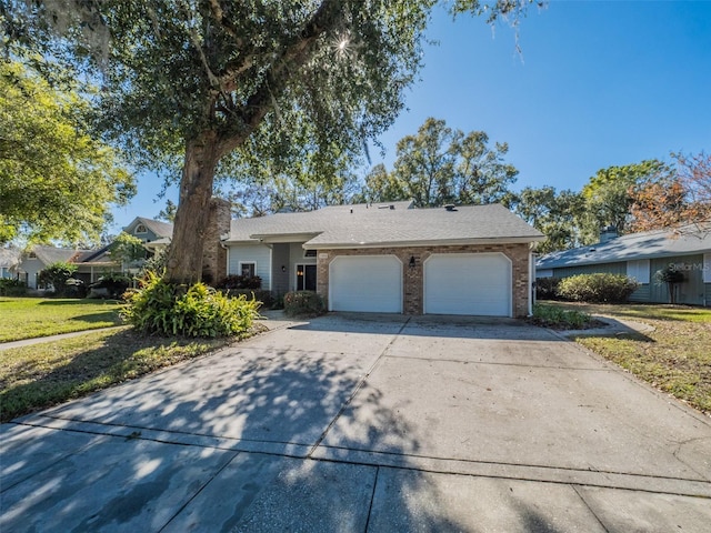 ranch-style home with concrete driveway, a garage, brick siding, and a front yard