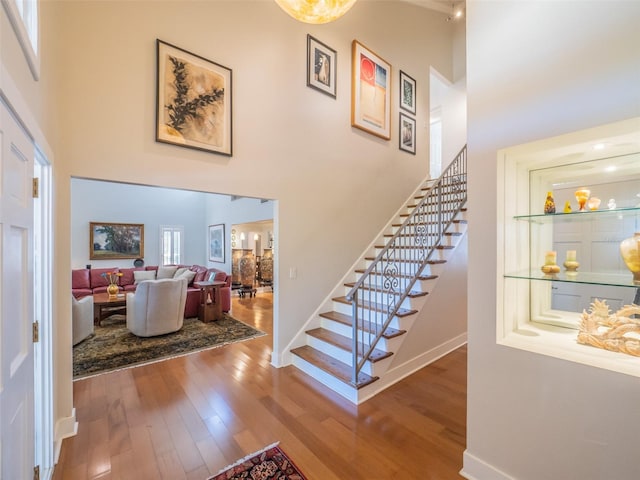 stairs with baseboards, a high ceiling, and wood finished floors