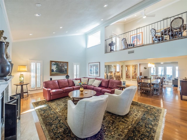 living room with crown molding, plenty of natural light, a fireplace, and wood finished floors