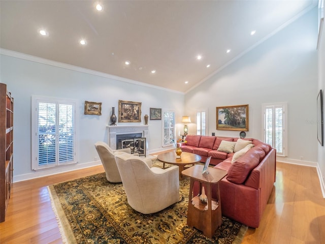 living room featuring a glass covered fireplace, crown molding, light wood-style floors, and baseboards