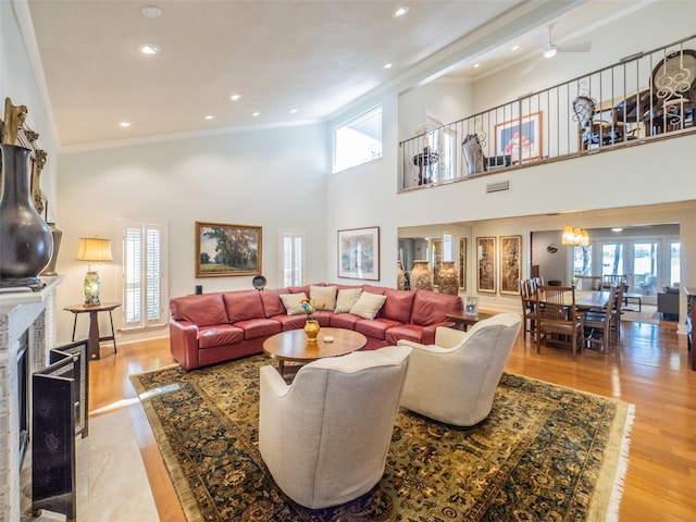 living area featuring a brick fireplace, wood finished floors, and ornamental molding