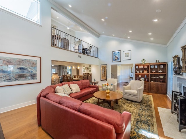 living room featuring wood finished floors, high vaulted ceiling, a fireplace, recessed lighting, and ornamental molding