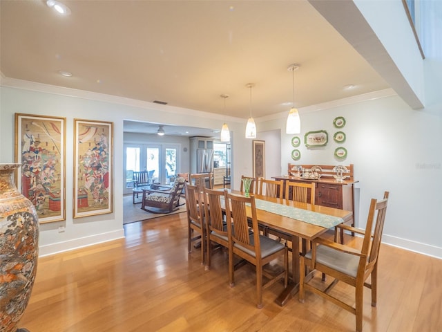 dining room featuring visible vents, baseboards, ornamental molding, and light wood finished floors