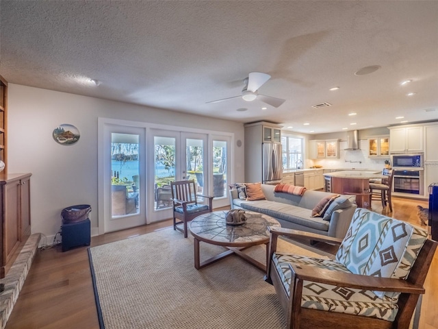 living room with ceiling fan, recessed lighting, french doors, wood finished floors, and a textured ceiling