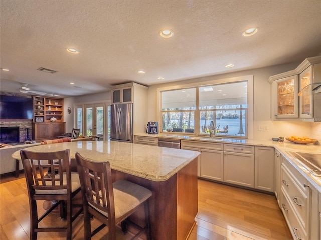 kitchen with visible vents, light wood-type flooring, a sink, open floor plan, and appliances with stainless steel finishes