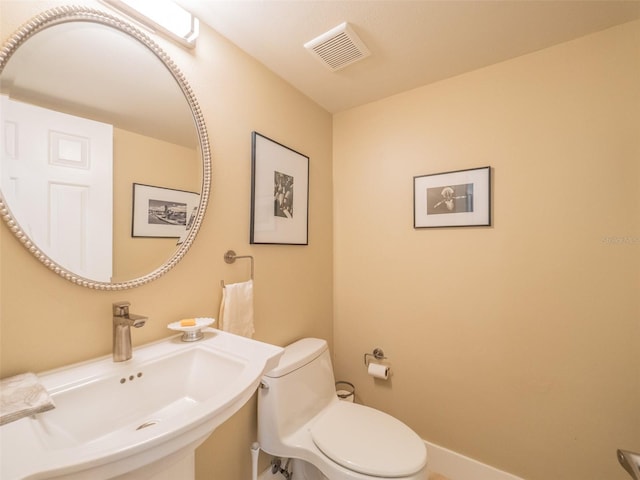 bathroom with visible vents, toilet, and a sink