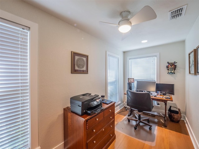 home office with visible vents, baseboards, wood finished floors, and a ceiling fan