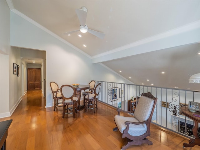 dining area with wood finished floors, baseboards, lofted ceiling, and ornamental molding