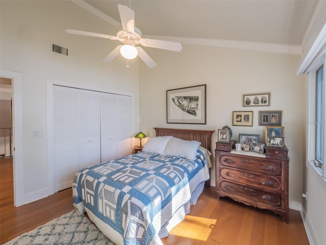 bedroom with visible vents, wood finished floors, a closet, baseboards, and ceiling fan