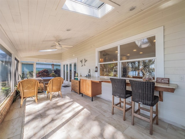 sunroom / solarium with lofted ceiling with skylight, wood ceiling, and ceiling fan