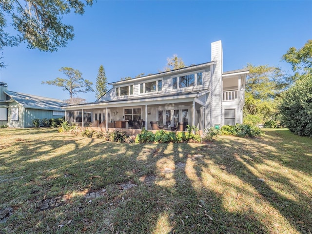 rear view of house featuring a lawn, a chimney, and a sunroom