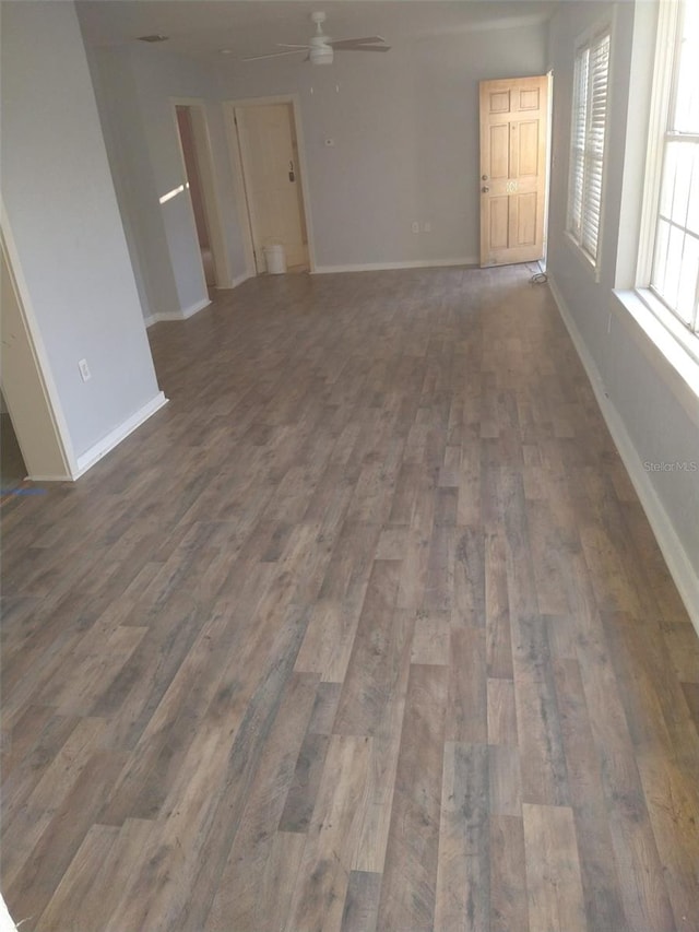 interior space with a ceiling fan, baseboards, and wood finished floors