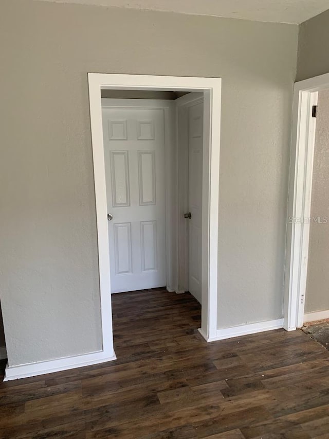 hall with baseboards, dark wood-style flooring, and a textured wall