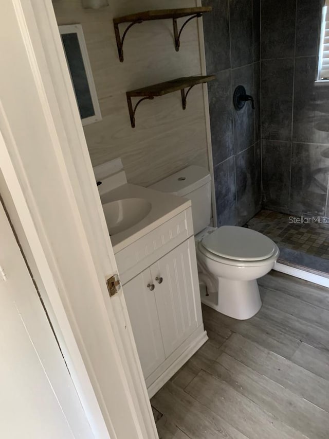 full bathroom with vanity, a shower stall, toilet, and wood finished floors