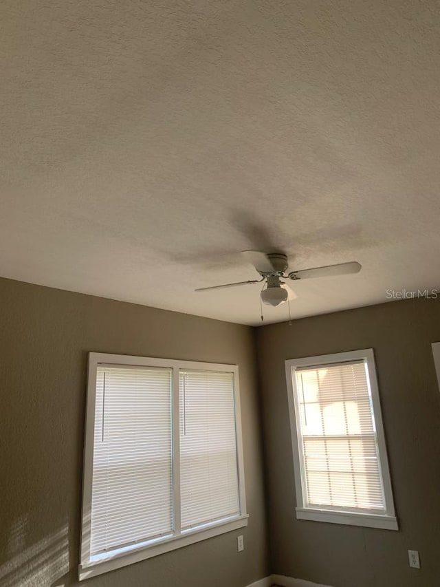 spare room featuring a textured ceiling and a ceiling fan