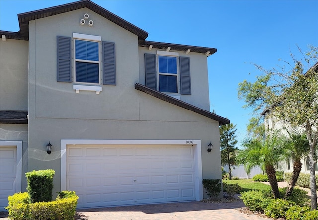 exterior space with decorative driveway, a garage, and stucco siding