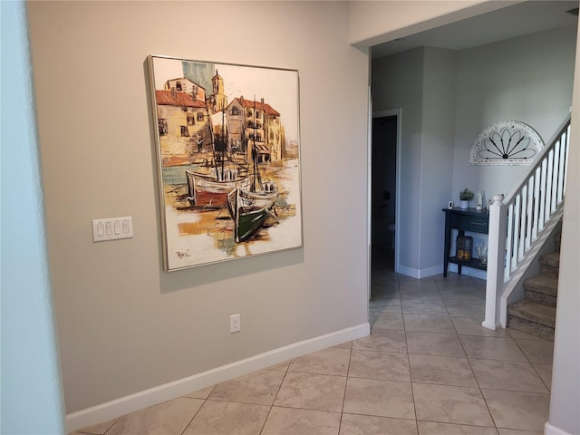 corridor featuring tile patterned floors, stairway, and baseboards