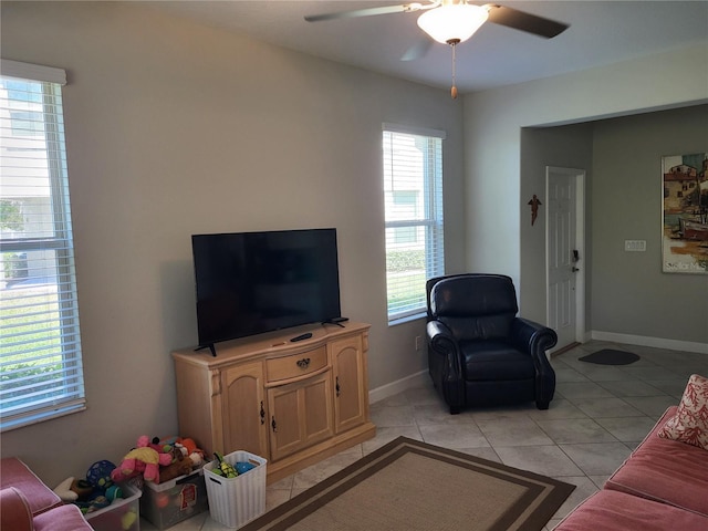 living area featuring light tile patterned floors, baseboards, and ceiling fan