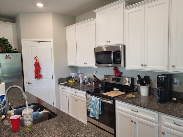 kitchen featuring a sink, dark stone counters, appliances with stainless steel finishes, and white cabinetry