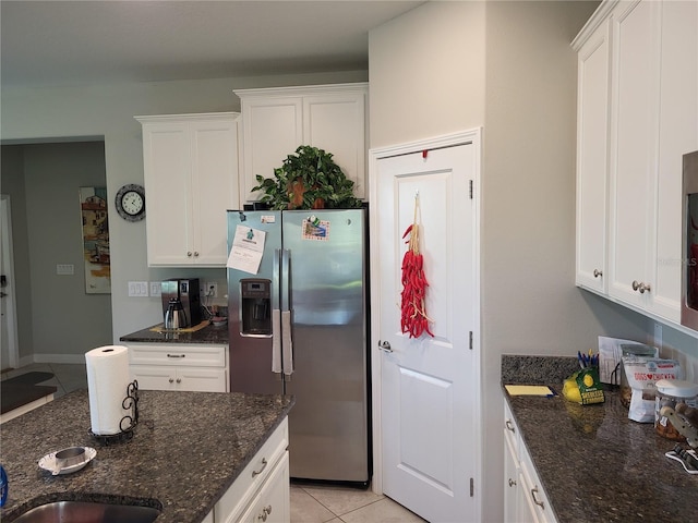 kitchen with dark stone countertops, light tile patterned floors, stainless steel refrigerator with ice dispenser, and white cabinetry