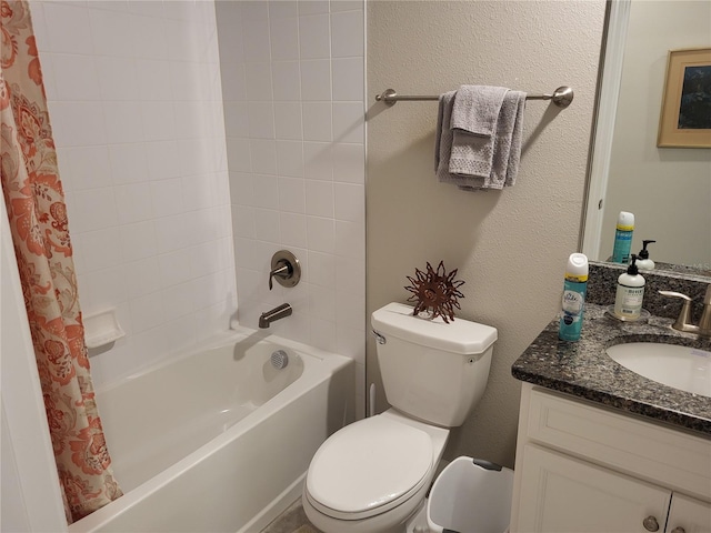 full bath with toilet, vanity, a textured wall, and shower / bath combo