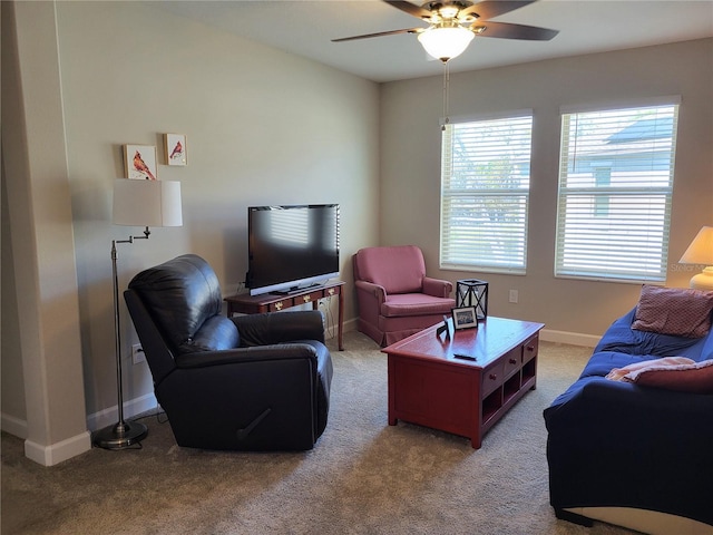 living area featuring baseboards, light carpet, and ceiling fan