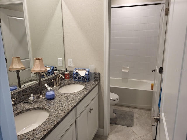 full bath featuring double vanity, toilet, a textured wall, and a sink