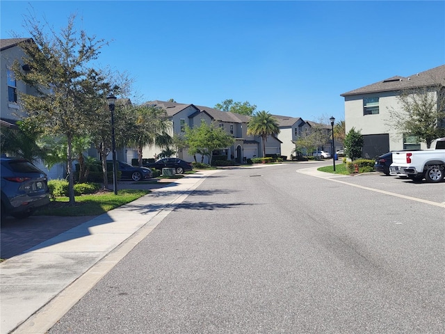 view of road with a residential view, street lights, and sidewalks