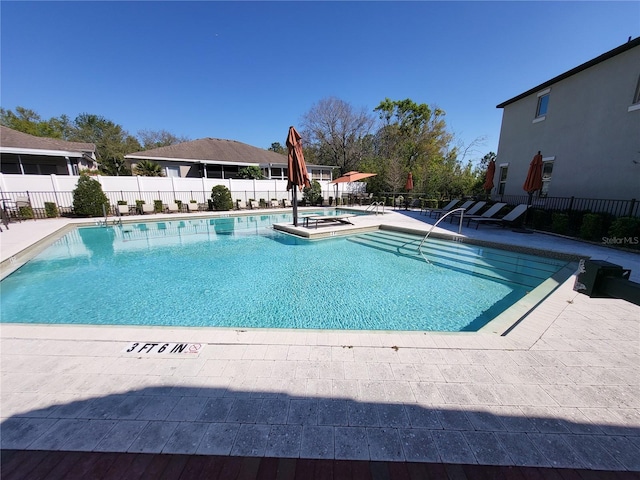 community pool featuring fence, a hot tub, and a patio area