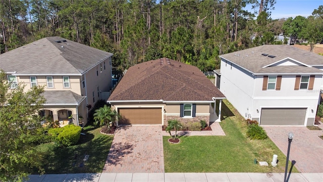 traditional-style house with stone siding, a front lawn, decorative driveway, and a garage