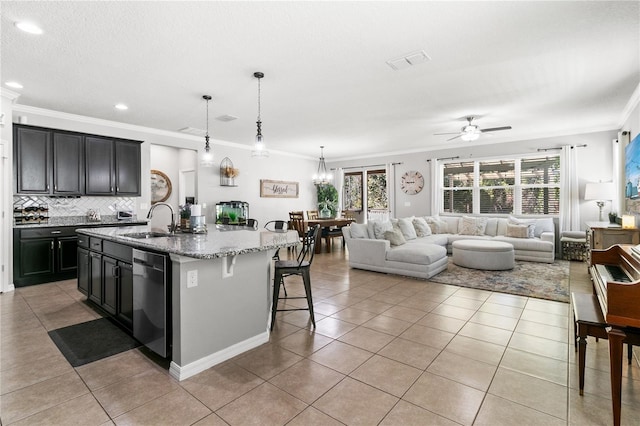 kitchen featuring visible vents, a breakfast bar, a sink, stainless steel dishwasher, and open floor plan