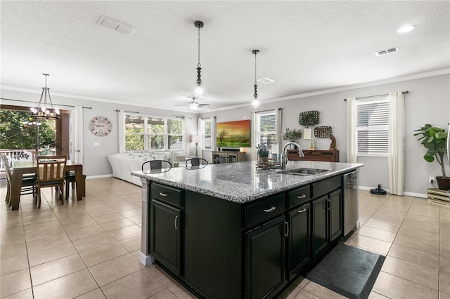 kitchen with light tile patterned floors, visible vents, a sink, crown molding, and dark cabinets