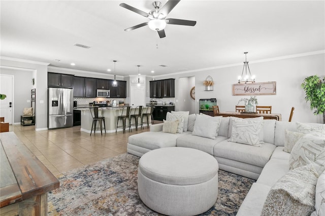 living room with visible vents, ornamental molding, ceiling fan with notable chandelier, light tile patterned flooring, and baseboards