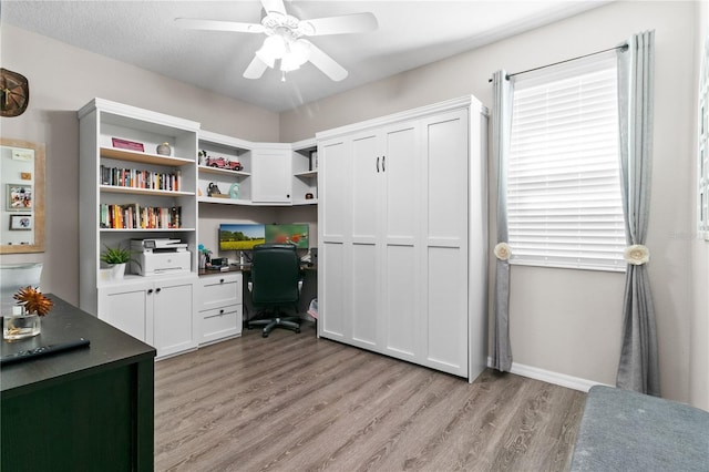 office with built in desk, light wood finished floors, and ceiling fan