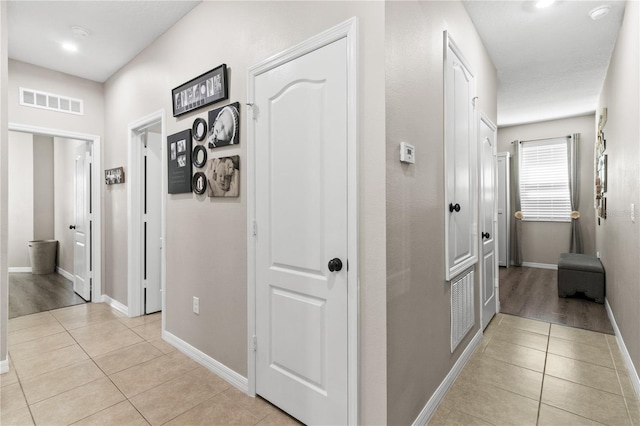 hallway with light tile patterned floors, baseboards, and visible vents