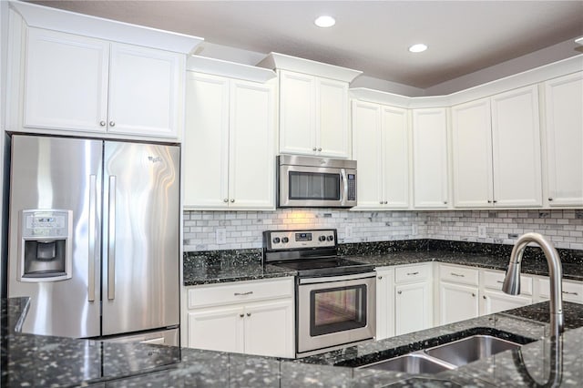 kitchen with backsplash, white cabinetry, stainless steel appliances, and a sink