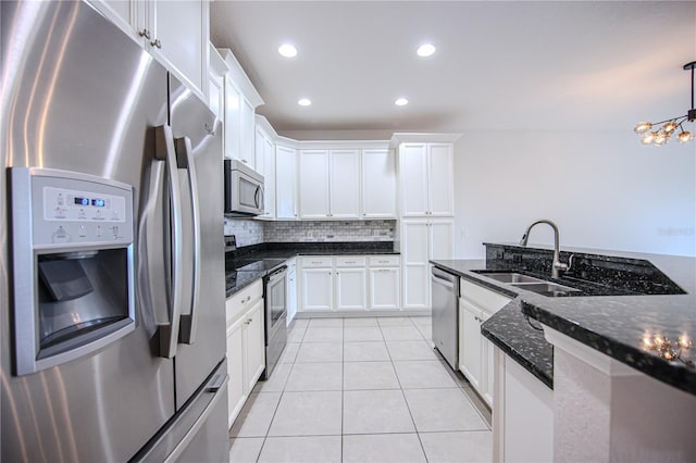 kitchen with light tile patterned floors, a sink, stainless steel appliances, white cabinets, and backsplash