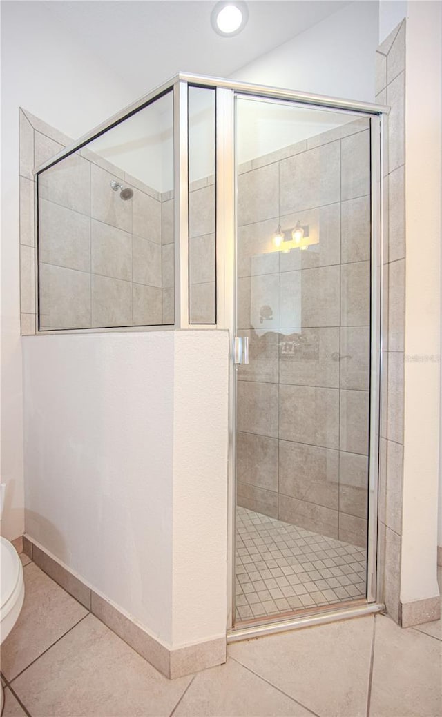 bathroom featuring tile patterned flooring, a shower stall, and toilet