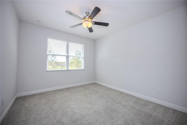 carpeted empty room with ceiling fan and baseboards