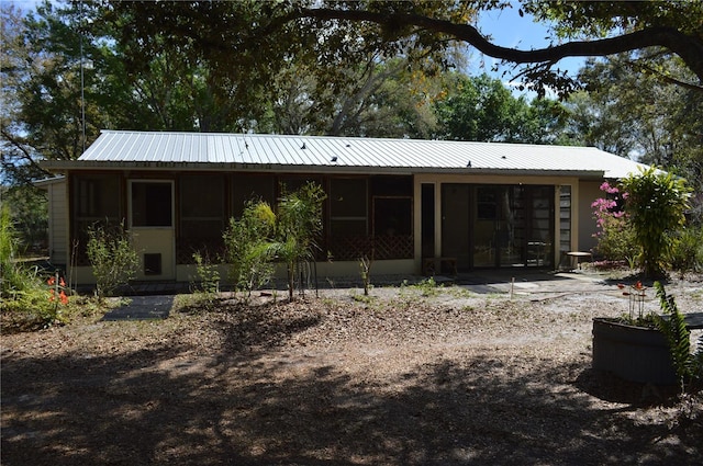 rear view of property featuring a sunroom and metal roof