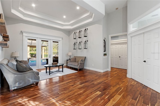 living area with wood finished floors, visible vents, baseboards, french doors, and a raised ceiling