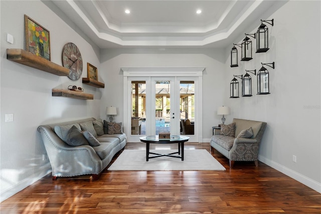 living area with a tray ceiling, wood finished floors, baseboards, and french doors