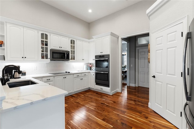 kitchen featuring dark wood finished floors, a sink, stainless steel appliances, white cabinets, and glass insert cabinets