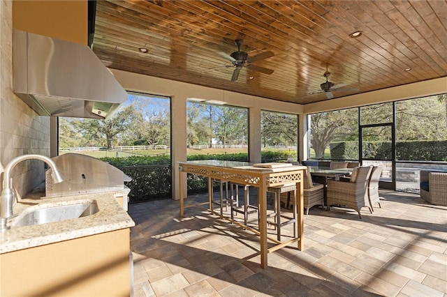 sunroom / solarium with wooden ceiling, a ceiling fan, and a sink