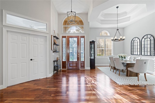 foyer entrance featuring baseboards, an inviting chandelier, wood finished floors, and ornamental molding