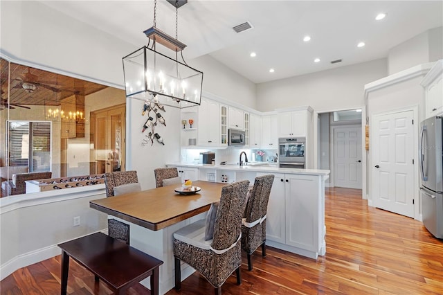 dining area with visible vents, light wood-style flooring, recessed lighting, an inviting chandelier, and a towering ceiling