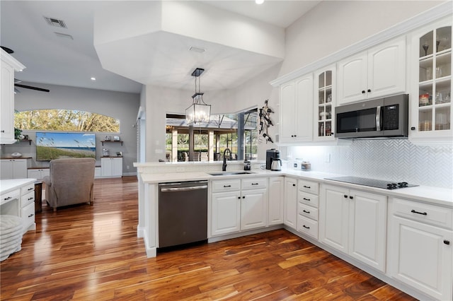 kitchen featuring an inviting chandelier, a peninsula, a sink, appliances with stainless steel finishes, and open floor plan