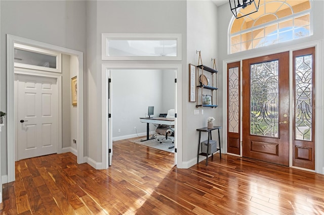 foyer with baseboards, a high ceiling, and hardwood / wood-style flooring